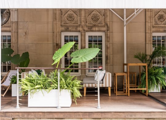 a terrace with chairs and potted plants in front of a building