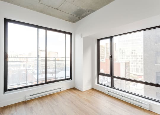 a living room with large windows and wood floors and a city view