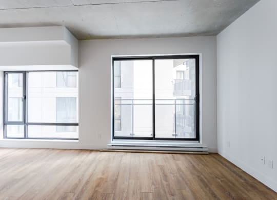 an empty living room with a large window and wooden floors