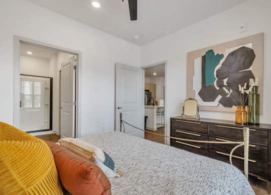 a spacious bedroom with a bed, dresser, and painting at Apex apartments in Colorado Springs, CO