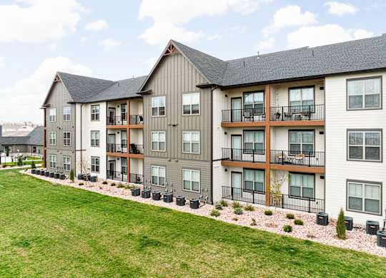 an exterior view of an apartment building with a green lawn