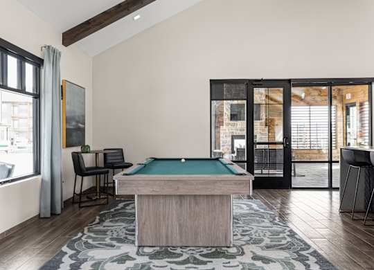 a pool table in a living room with a view of a patio