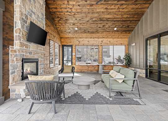 an outdoor living room with a stone fireplace and a tv
