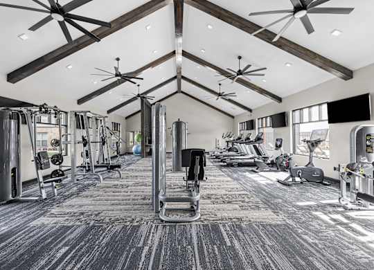 a gym with weights and cardio machines and ceiling fans