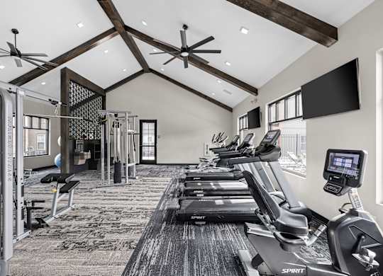 a gym with treadmills and weights and a tv
