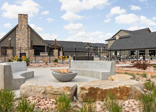 a patio with chairs and a fire pit in front of a building