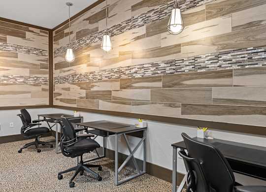 A modern office with wood paneling on the wall and black chairs.