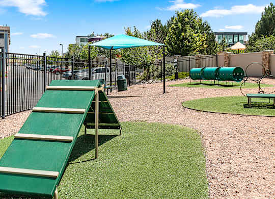 A playground with a green slide and a green umbrella.