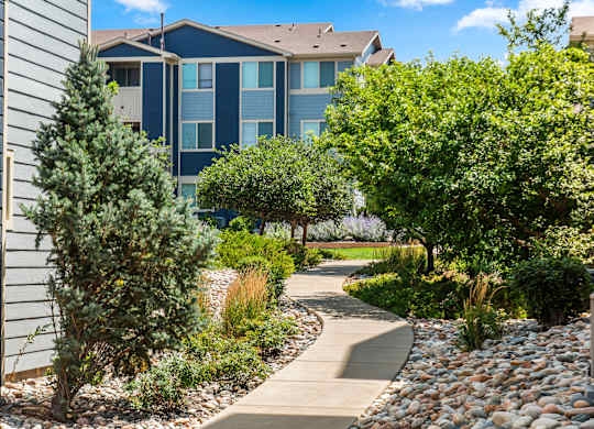 A pathway leads through a landscaped area with a building in the background.