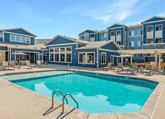 A large swimming pool in front of a building with a blue sky in the background.