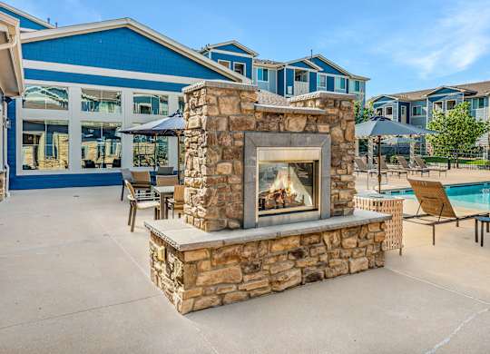 A stone fireplace is in the middle of a patio.