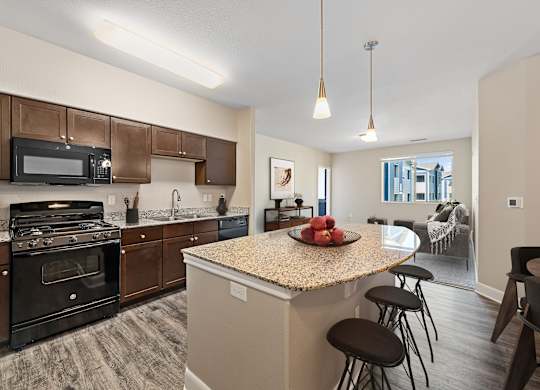 A kitchen with a granite countertop and bar stools.