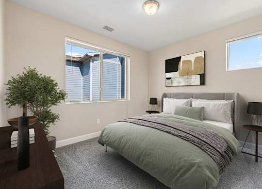 A bedroom with a bed, nightstand, and a plant.