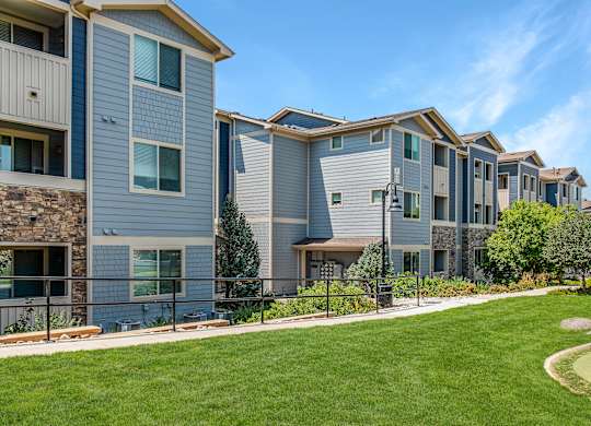 A row of modern townhouses with a well-maintained lawn in front.