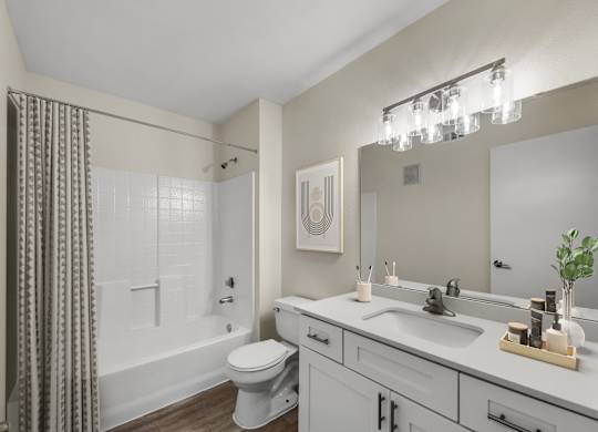 A bathroom with a white toilet, a white sink, and a white bathtub with a grey shower curtain.