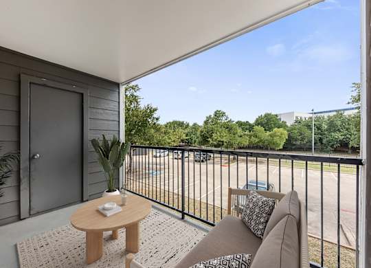 A balcony with a table and chairs overlooking a parking lot.
