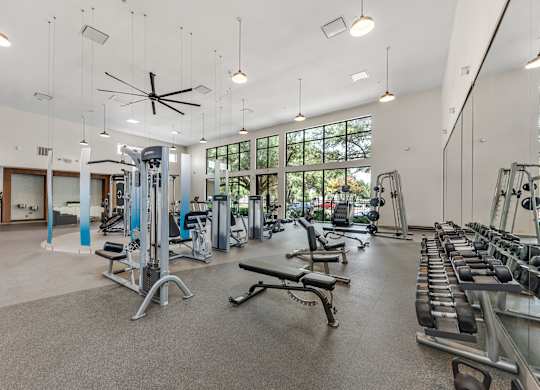 A spacious gym with a variety of equipment and a ceiling fan.