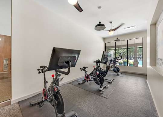 A room with exercise bikes and a ceiling fan.