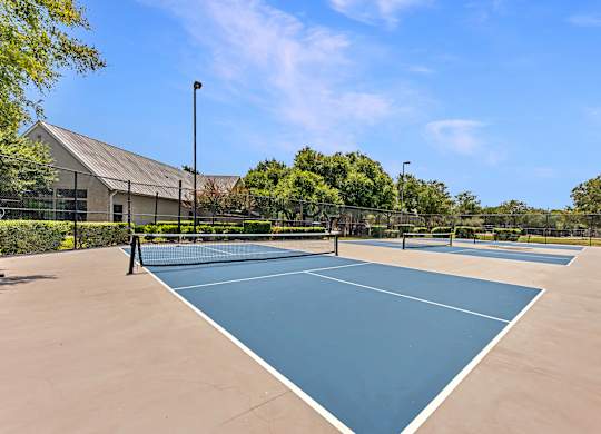 A tennis court surrounded by a fence and trees.