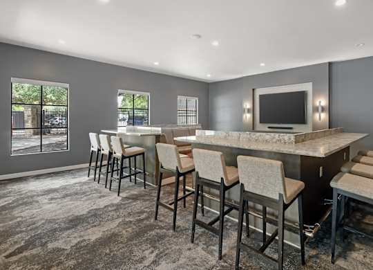 A theater room with a large TV, large table and chairs.
