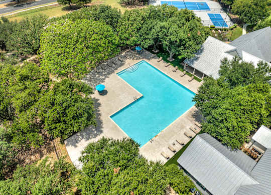 An aerial view of a swimming pool surrounded by trees.