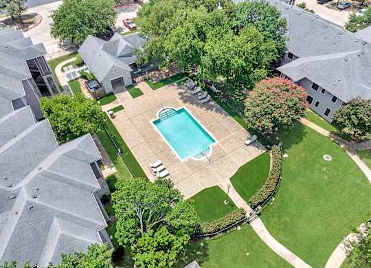 A swimming pool surrounded by a grassy area and trees.