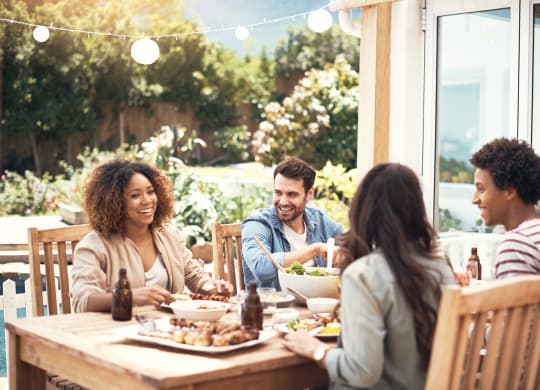 group of people sitting around a table talking and eating