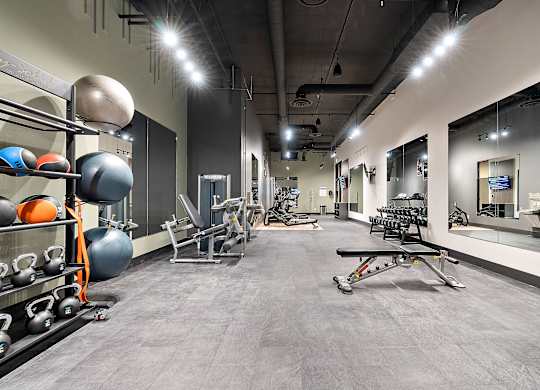 A gym with a variety of equipment including weights and a bench press.at Raymond Block, Edmonton Alberta T6E 3R7