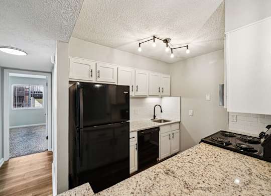 A kitchen with a black refrigerator and white cabinets.