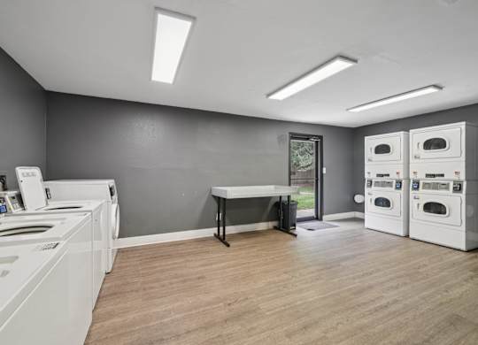 A laundry room with washers and dryers and a table.