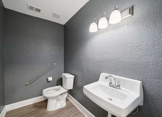 A bathroom with a toilet, sink, and lights.