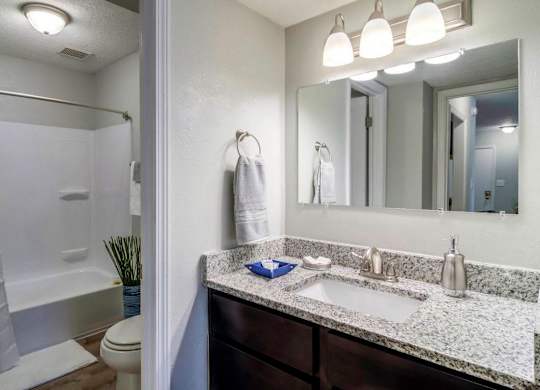 A bathroom with a marble countertop and a large mirror at The Onyx Hoover Apartments, Hoover, 35216