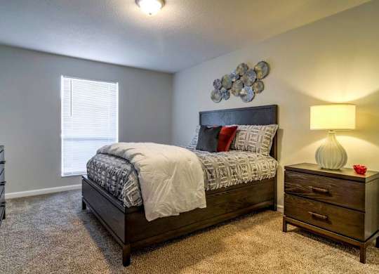 A bedroom with a bed, nightstand, and lamp at The Onyx Hoover Apartments, Hoover