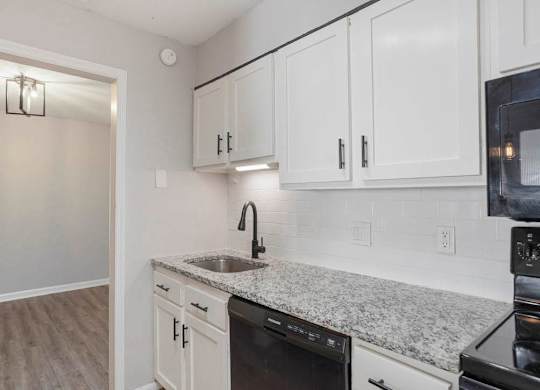 A kitchen with white cabinets and a granite countertop at The Onyx Hoover Apartments, Alabama, 35216
