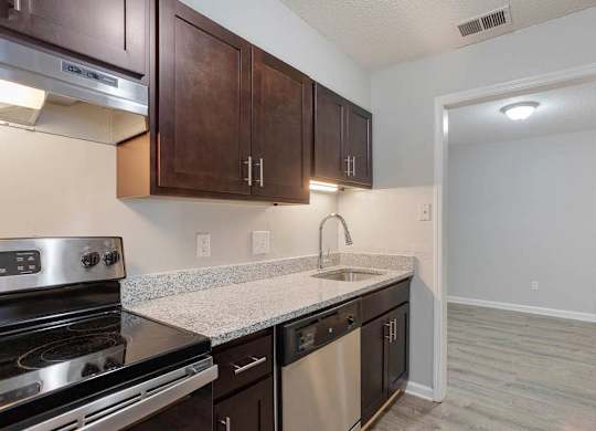 A kitchen with dark brown cabinets and stainless steel appliances at The Onyx Hoover Apartments, Hoover, Alabama