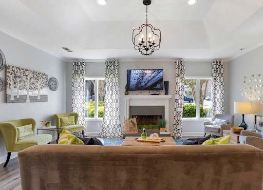 A living room with a brown couch and a chandelier at The Onyx Hoover Apartments, Hoover