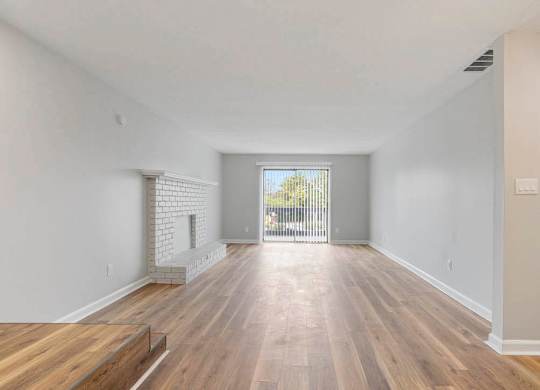 A spacious room with wooden flooring and a brick fireplace. at The Onyx Hoover Apartments, Alabama, 35216