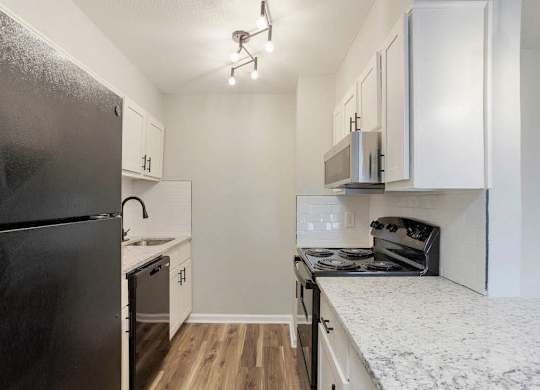 A kitchen with a black refrigerator and white cabinets. at The Onyx Hoover Apartments, Hoover, AL, 35216