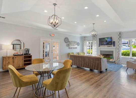 A modern dining room with a glass table and yellow chairs at The Onyx Hoover Apartments, Alabama