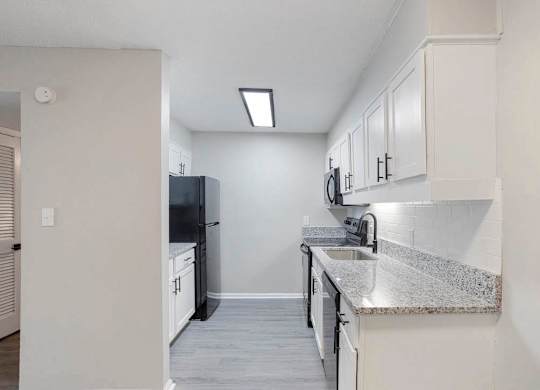 A kitchen with white cabinets and a black refrigerator at The Onyx Hoover Apartments, Alabama