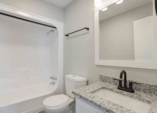 A white toilet sits next to a sink in a bathroom at The Onyx Hoover Apartments, Hoover, AL