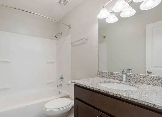 A white toilet sits next to a white sink in a bathroom at The Onyx Hoover Apartments, Hoover, AL, 35216