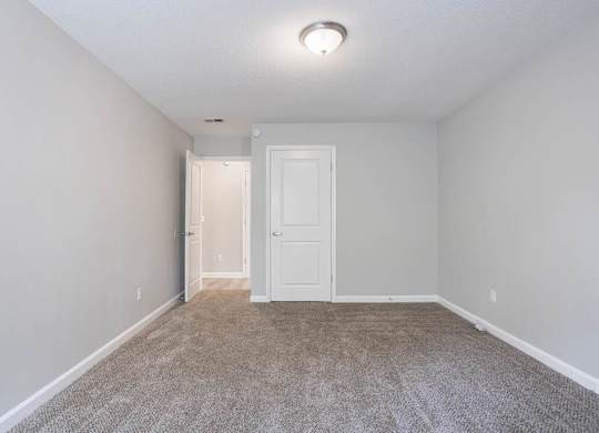 A room with a carpeted floor and a white door at The Onyx Hoover Apartments, Hoover, AL, 35216