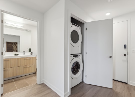 a front loader washer and dryer in a white room with a door open