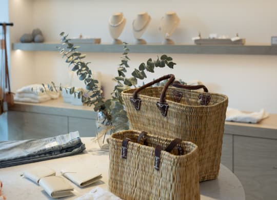 a table with three baskets and a shelf with ceramics on it