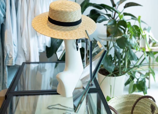 a straw hat sits on a glass table in a boutique