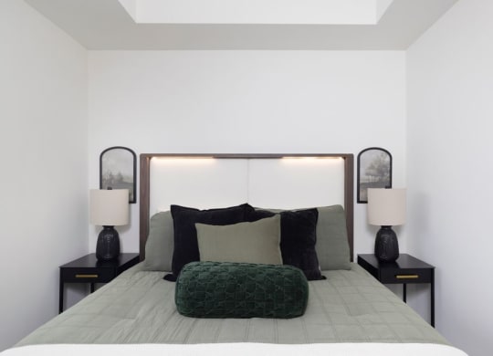 a white bedroom with a bed and a green pillow