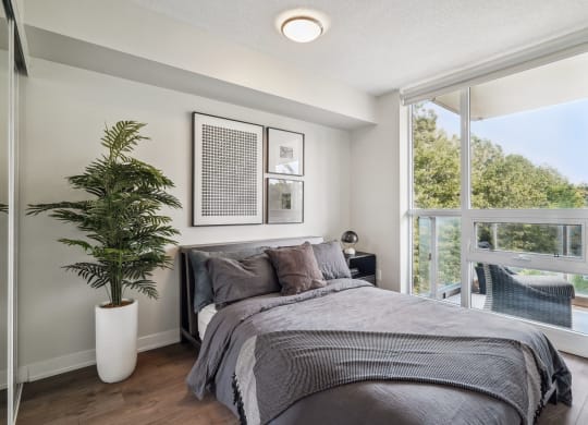 a bedroom with a large window and a plant