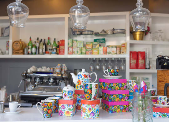 a kitchen with white cabinets and a counter with colorful cups and pitchers on it
