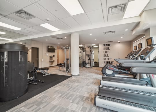 a gym with treadmills and other exercise equipment in a building with white ceilings